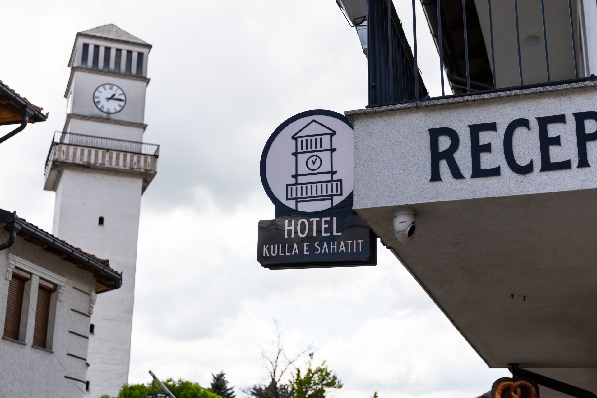 Hotel entrance signage with the Clock Tower of Gjakova behind