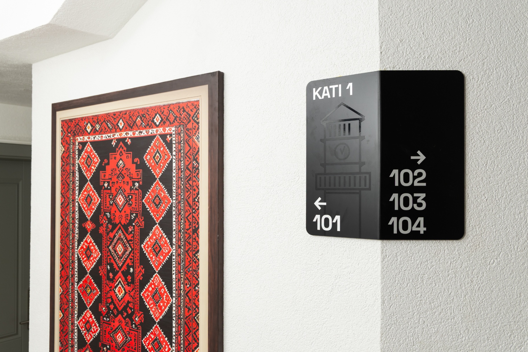 Guest floor wayfinding sign beside a framed traditional carpet
